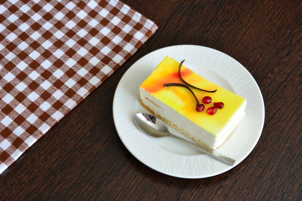 lemon cake decorated with chocolate and pomegranate seeds on plate on dark wooden table