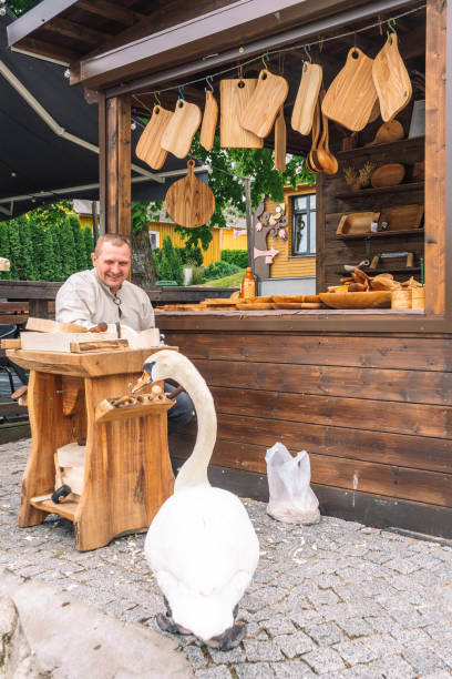 litewski rzemieślnik w tradycyjnych strojach rzeźbiący drewno i sprzedający swoje ręcznie robione drewniane artefakty - troki zdjęcia i obrazy z banku zdjęć