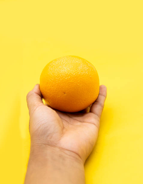 istock Orange in a human hand over on white background. 1400983579
