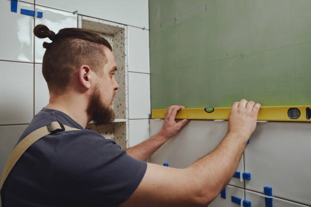 istock Tiler checks tile laying with building measuring level 1400985002