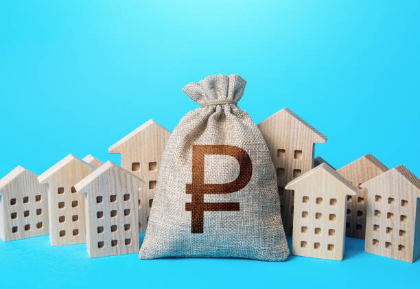 Russian ruble money bag among town houses figurines. Rich city. Rental business. Real Estate Agent services. Sale of real estate. property taxes. Tax collection, investment in development. Municipal budgeting. bolsa de dinero de rublo ruso entre figuritas de casas de pueblo. ciudad rica. negocio de alquiler. servicios de realtor. venta de inmuebles. impuestos a la propiedad. recaudación de impuestos, inversión en desarrollo. presupuestos municipales.