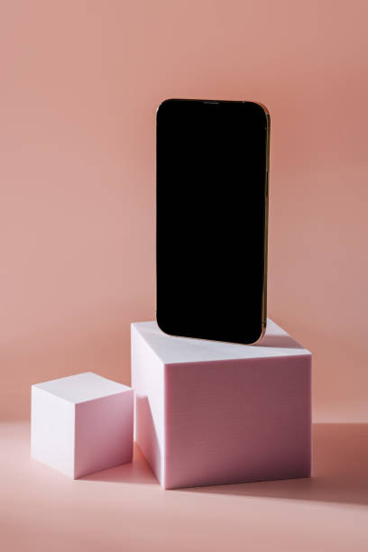 istock Smartphone with blank black screen. Mobile phone on cube podium.  Pedestal mockup space for display of app. 1400985948