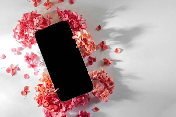 istock Smartphone mockup with pink flowers on white background. Device screen mock up on stylish background for presentation or appl design 1400985954