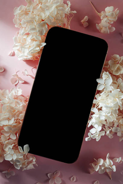 istock Smartphone mockup with white flowers on  pink   background. Device screen mock up on stylish background for presentation or appl design 1400985988