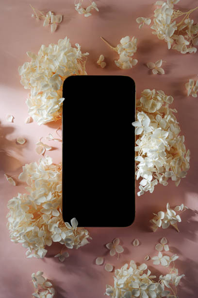 istock Smartphone mockup with white flowers on  pink   background. Device screen mock up on stylish background for presentation or appl design 1400985990