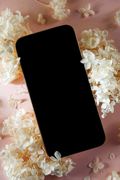 istock Smartphone mockup with white flowers on  pink   background. Device screen mock up on stylish background for presentation or appl design 1400985991