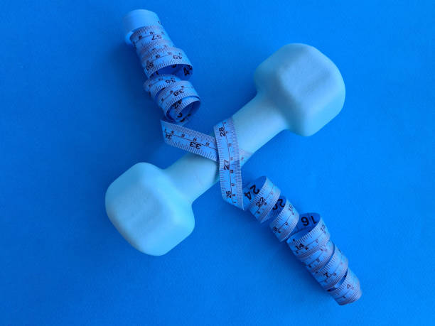 istock Sports dumbbell and centimeter on blue background 1400986326