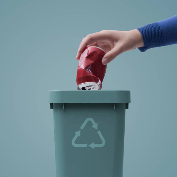 istock Woman putting a can in a garbage bin 1400990560
