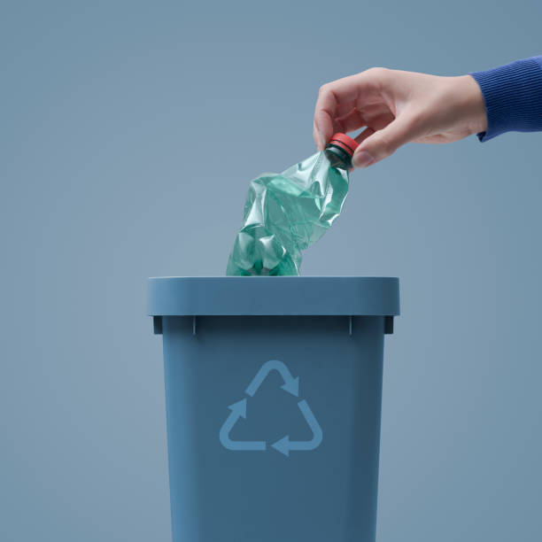 istock Woman putting a plastic bottle in a trash bin 1400991047