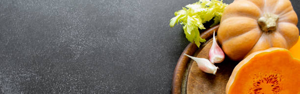 istock Banner vegetables on cutting board: orange squash, celery, garlic. Black background. Copy space 1400992852