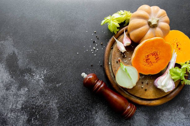 istock Vegetables: orange squash, garlic, onions. Spice mill, pepper, salt. Black background. Copy space 1400992876