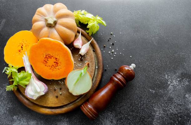 istock Vegetables: orange squash, garlic, onions. Spice mill, pepper, salt. Black background. Copy space 1400992918