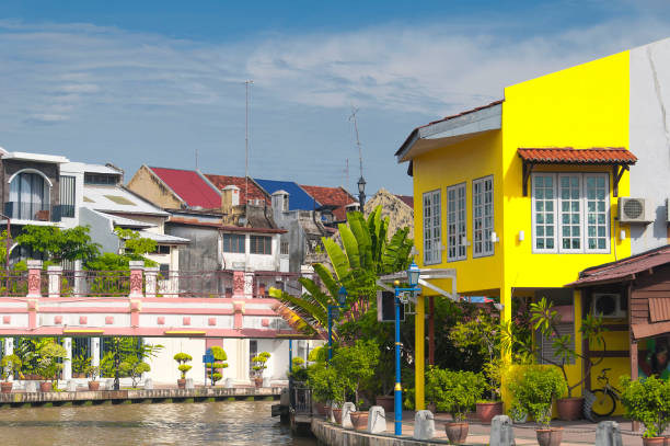 Colorful buildings lining the Melaka River in the city of Malacca Malaysia on a blue sky day.