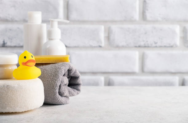 Baby hygiene accessories in home bathroom. Rubber toy, cosmetic cream, soap, sponge, shampoo bottle and towel. Copy space, close up sponge bath sponge nature animal stock pictures, royalty-free photos & images