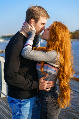 Una joven pareja está de pie en la orilla del río abrazándose photo