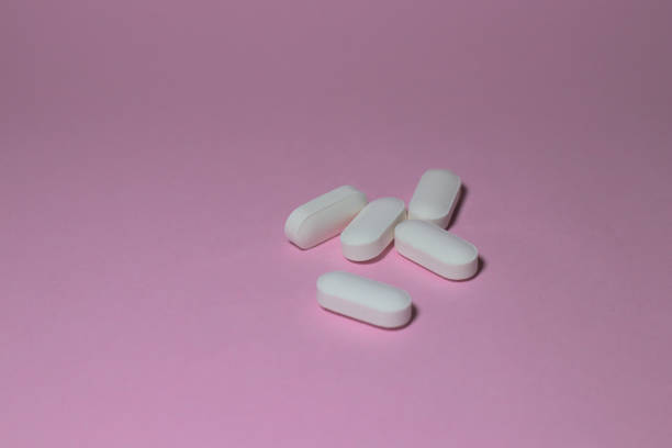 istock white medicine or drugs scattered on pink surface 1401002156