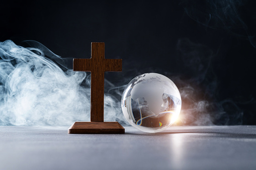 Earth globe and wooden cross in the table.