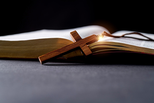 Wooden cross and bible on the table.
