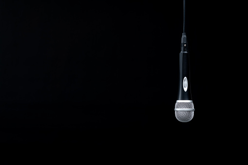 Microphone hanging on black background.