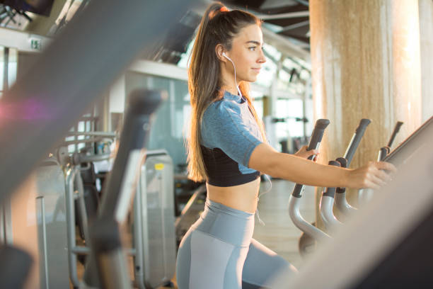 istock Active young woman exercising on elliptical trainer machine at gym 1401008511