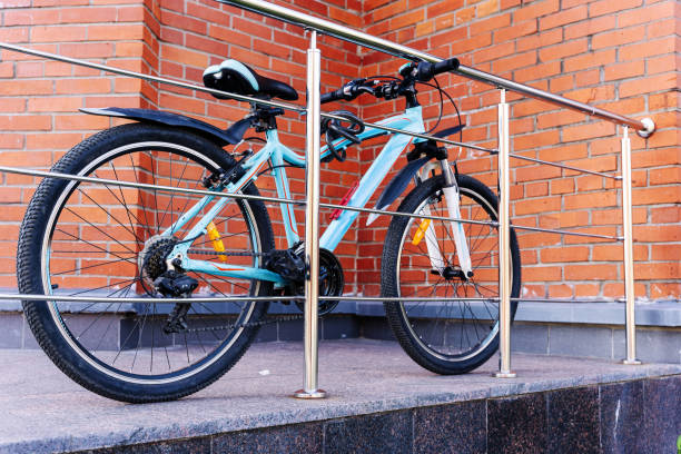 bike is tied with a bicycle lock to the fence on background of wall stock photo