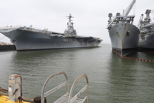 An armed guard looks up at the MV-22 Osprey aircraft while patrolling the deck of USS Tripoli (LHA 7) of the US Navy docked at Garden Island, Sydney Harbour.  This image was taken from Mrs Macquarie's Chair on an afternoon in Spring.