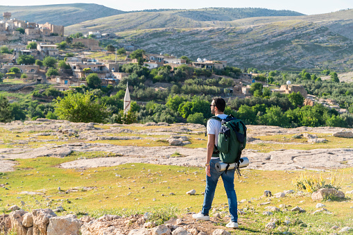 Backpacking man hiking in the Dara Ruins in Mardin province, looking at the view of the historical village. Taken with a full-frame camera in sunny weather.