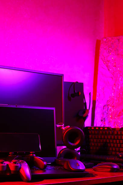 istock Gamer's workspace. Gamepads, computer mouse, headphones, keyboard and laptop on the table. Gaming accessories and computer equipment in neon light. Gambling addiction concept 1401016208