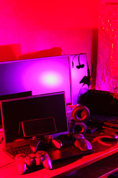 istock Gamer's workspace. Gamepads, computer mouse, headphones, keyboard and laptop on the table. Gaming accessories and computer equipment in neon light. Gambling addiction concept 1401016210