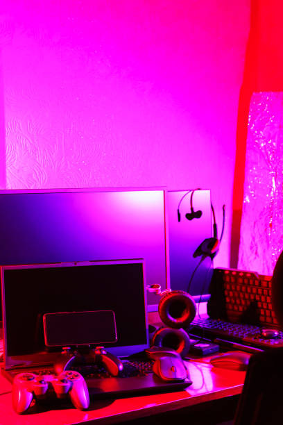 istock Video game controller, computer mouse, headphones, keyboard and laptop. Workspace with gaming accessories and computer equipment in neon light. Gamer work space concept 1401017004