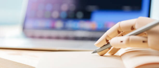istock Robotic hand holding a pencil near a notebook. Robot arm works next to open laptop. Artificial intelligence technology concept. Copy space 1401018506