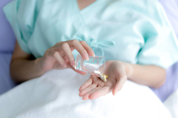Hand taking pills to treat sickness at the hospital. stock photo