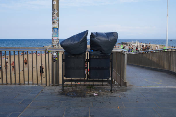 Trash bag with bin inflated by wind. Mess on the ground. Beach and sea on the background stock photo