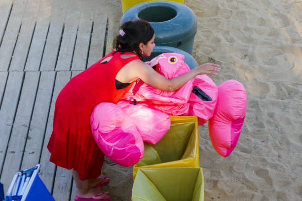 Broken inflatable sea animal. Deflated broken water baloon toy on the beach. Rubbish and bin. Mom stock photo