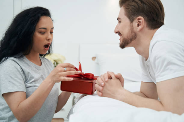 istock Man observing astonished woman opening his present 1401020837