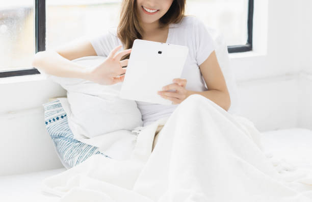 istock Unrecognizable happy young woman use tablet computer and scrolling through tablet on bed at bedroom with happiness Pretty girl using tablet for social media shopping online study and watching movie 1401022527