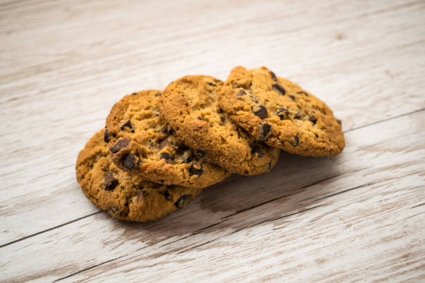 biscotti con gocce di cioccolato in linea su un tavolo di legno - biscotti cookie morning temptation foto e immagini stock