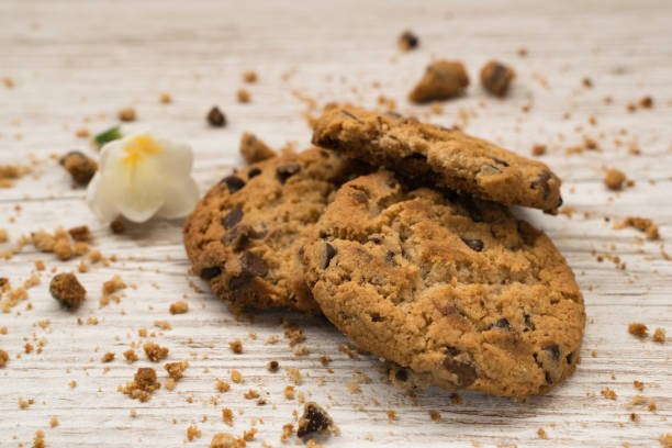 biscotti con gocce di cioccolato accanto a un fiore su un tavolo di legno - biscotti cookie morning temptation foto e immagini stock