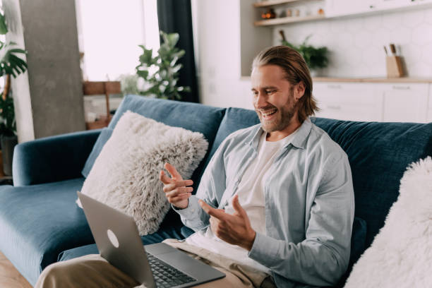 istock video conference with loved ones online. A young guy communicates via video link at home sitting on the couch 1401023382