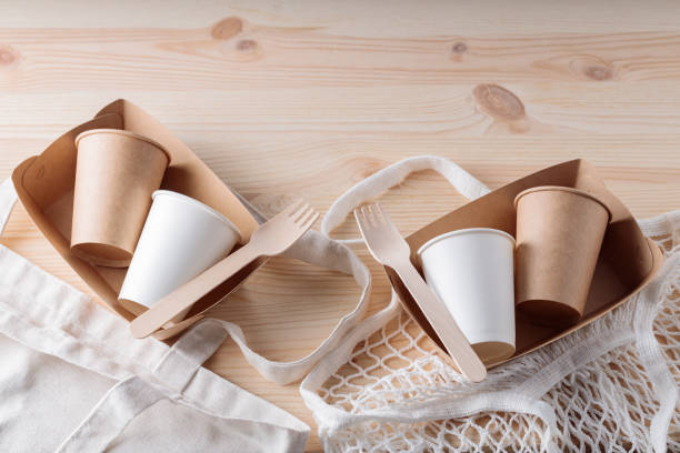istock Wooden cutlery, paper disposable tableware and mesh bag. Eco friendly kitchen utensils and linen shopping bag on a wooden table. Zero waste or plastic free concept 1401023405