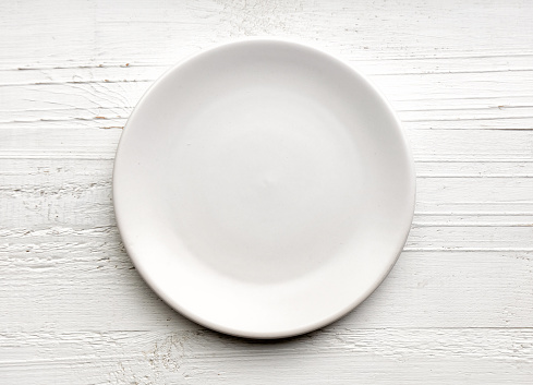 empty white plate on white wood background, top view