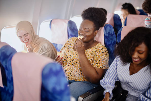 istock Friends sitting next to each other on an airplane chatting back and forth and sharing snacks 1401027322