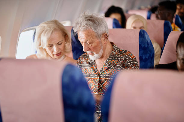 istock Senior couple watch something on a smartphone while traveling with plane 1401027343