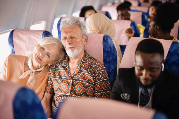 istock Senior woman resting on her husband's shoulder while traveling by plane 1401027354