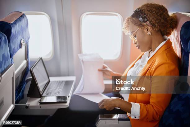 Businesswoman Reading Documents And Working On Digital Tablet During Flight Stock Photo - Download Image Now