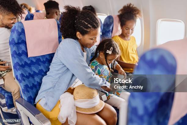 The Mother Helps The Child To Fasten Seat Belt On The Plane Stock Photo - Download Image Now