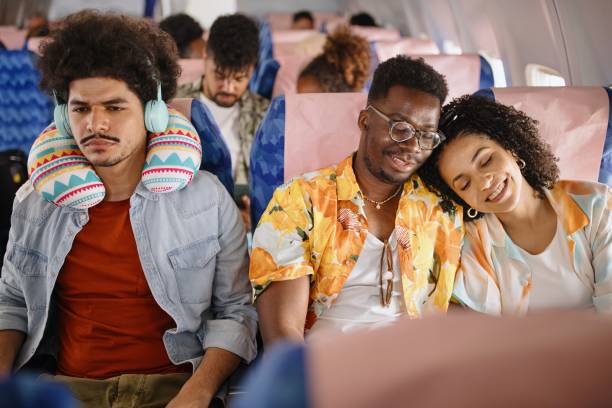 Young woman sleeping on her boyfriend's shoulder while traveling by plane