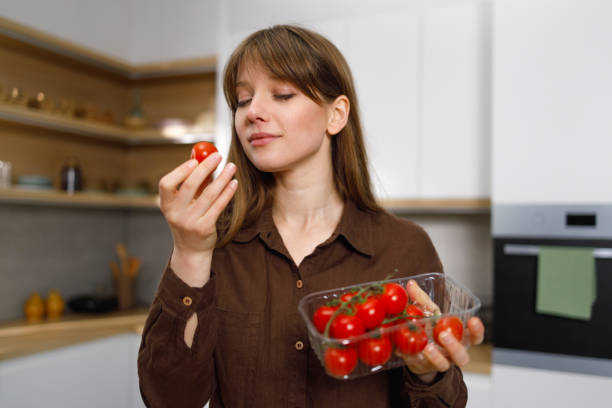 istock Young vegan woman examining cherry tomatoes while standing in the kitchen 1401028630