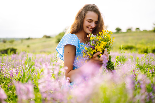 woman in a field with flowers- freedom,  active,  happiness concept