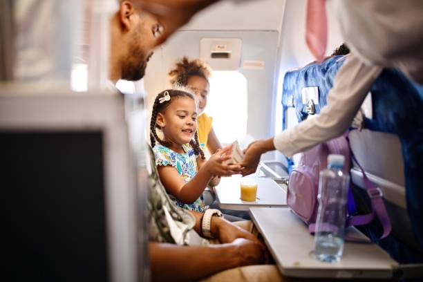 hostess che servono cibo e bevande alla famiglia sull'aereo durante il volo - cabin crew foto e immagini stock